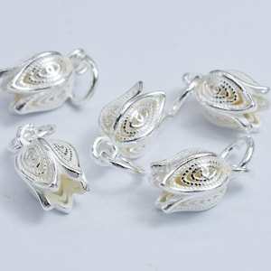 Peut inclure: Cinq breloques en forme de fleur argentées avec des motifs complexes. Les breloques ont une boucle en haut pour les attacher à des bijoux.