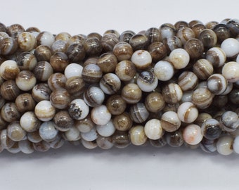 May include: A strand of round, white agate beads with brown and black stripes. The beads are approximately 6mm in diameter.