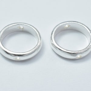 May include: Two silver rings with a small hole in the centre of each ring.