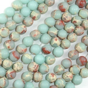 May include: A strand of light blue and white marbled round beads with red accents. The beads are approximately 10mm in diameter.
