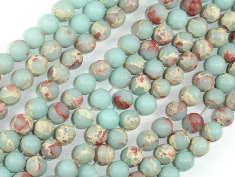 May include: A strand of light blue and white marbled round beads with red accents. The beads are approximately 10mm in diameter.