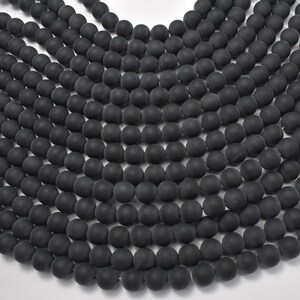 May include: A strand of black matte round beads. The beads are uniform in size and have a smooth, polished finish.