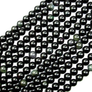 May include: A strand of black obsidian beads with a subtle green shimmer. The beads are round and smooth, and they are arranged in a staggered pattern.