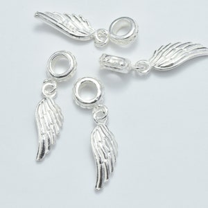Peut inclure: Quatre breloques en argent en forme d'ailes d'ange avec une boucle pour les attacher à un bracelet ou un collier.