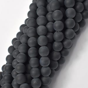 May include: A strand of black matte round beads. The beads are smooth and have a slightly textured surface.