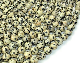May include: A strand of round, white and black dalmatian jasper beads. The beads are approximately 8mm in diameter and have a speckled pattern.