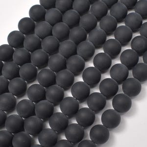 May include: A strand of black matte round beads. The beads are smooth and have a uniform size and shape.