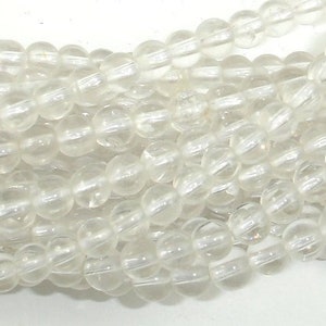 May include: A strand of clear quartz beads. The beads are round and have a smooth, polished finish. The beads are strung on a clear thread.