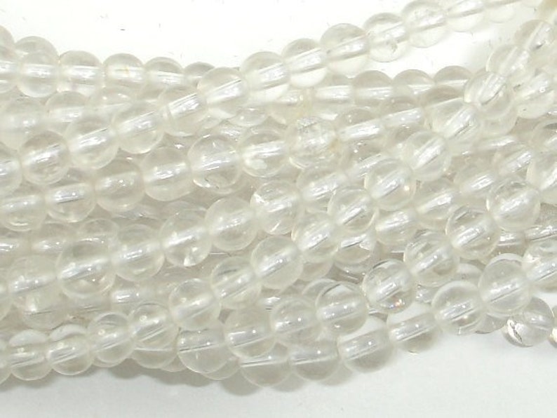 May include: A strand of clear quartz beads. The beads are round and have a smooth, polished finish. The beads are strung on a clear thread.