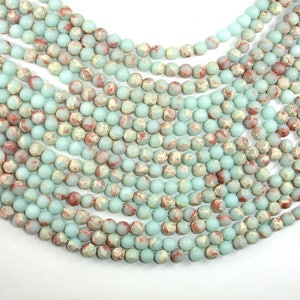 May include: A strand of light blue and brown marbled round beads. The beads are approximately 6mm in diameter and have a matte finish.