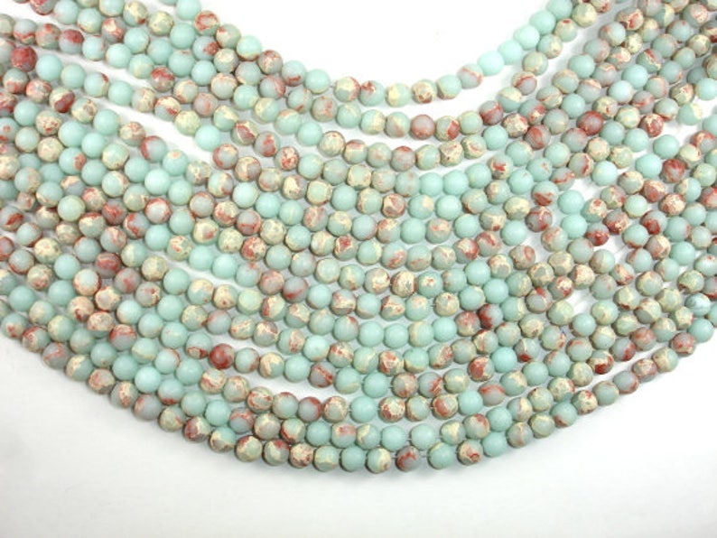 May include: A strand of light blue and brown marbled round beads. The beads are approximately 6mm in diameter and have a matte finish.