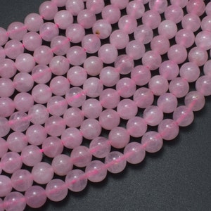 May include: A strand of pink rose quartz beads. The beads are round and smooth, and they have a natural, slightly translucent appearance.