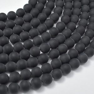 May include: A strand of matte black round beads. The beads are smooth and have a uniform size and shape.