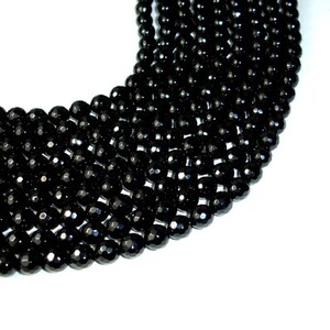 May include: A strand of black faceted gemstone beads. The beads are round and have a shiny finish.