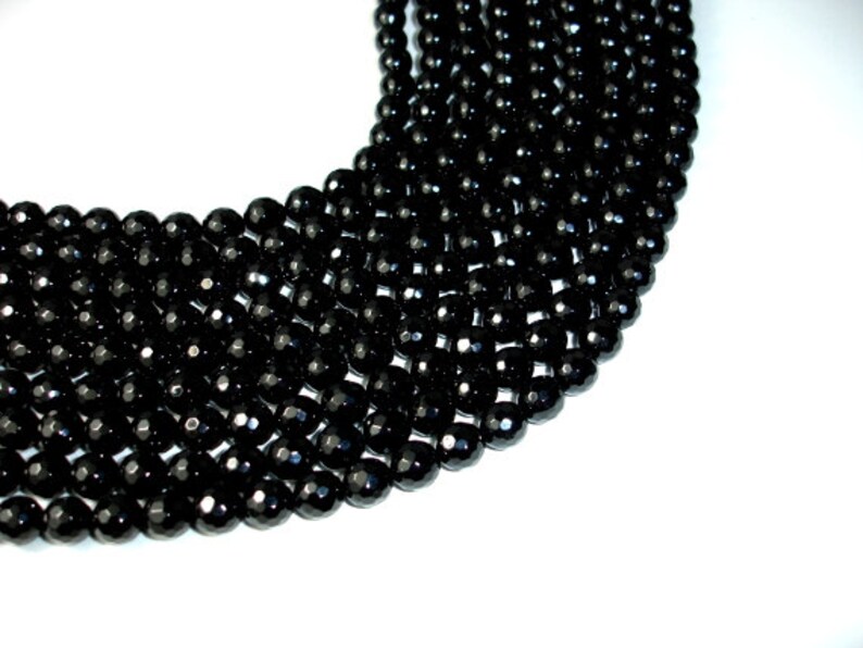 May include: A strand of black faceted gemstone beads. The beads are round and have a shiny finish.