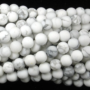 May include: A strand of white howlite beads with grey veining. The beads are round and smooth, and they are strung on a clear thread.