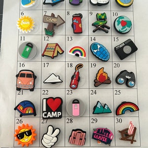 May include: A set of 30 colorful camping-themed shoe charms. The charms include a variety of camping icons, such as a tent, a campfire, a compass, a backpack, a camper van, and a pair of binoculars. The charms are arranged in a grid on a white background, with numbers 1 through 30 labeling each charm.