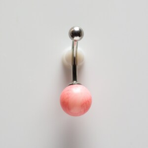 May include: A silver belly button ring with a pink round gem.