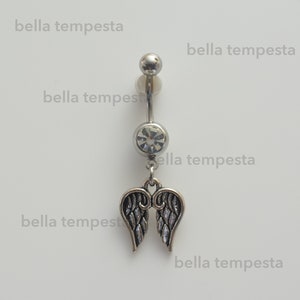 May include: Silver belly button ring with a clear crystal and a dangling pair of angel wings.