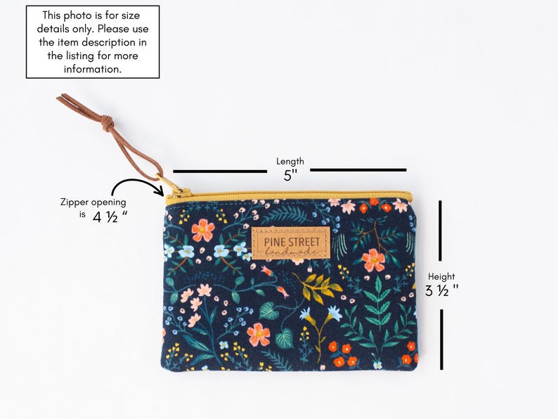 May include: A navy blue floral print pouch with a gold zipper and a leather wrist strap. The pouch is 12.7 cm long and 8.9 cm high. The zipper opening is 11.4 cm. The label reads "PINE STREET handmade."