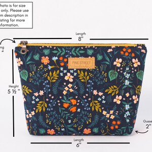 Peut inclure: Une pochette zipp&eacute;e bleu marine fonc&eacute; avec un imprim&eacute; floral color&eacute; compos&eacute; de fleurs orange, roses et bleu clair sur un feuillage vert. Elle mesure 8 pouces de long, 5,5 pouces de haut, avec une ouverture de fermeture de 6,5 pouces et un soufflet de 2 pouces.