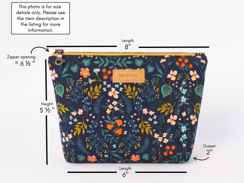 Peut inclure: Une pochette zipp&eacute;e bleu marine fonc&eacute; avec un imprim&eacute; floral color&eacute; compos&eacute; de fleurs orange, roses et bleu clair sur un feuillage vert. Elle mesure 8 pouces de long, 5,5 pouces de haut, avec une ouverture de fermeture de 6,5 pouces et un soufflet de 2 pouces.