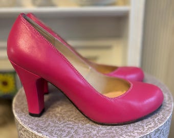 May include: A pair of bright pink high-heeled pumps with a closed toe and a chunky heel.