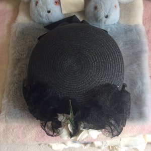 May include: A black straw hat with a black lace trim and white flower accents.