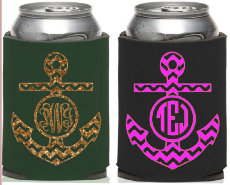Op de afbeelding: Twee blikjeskoelers, &eacute;&eacute;n donkergroen met een gouden glitteranker en monogram, de andere zwart met een roze anker en monogram. Ontworpen om dranken koel te houden.