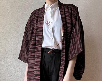 May include: A burgundy and black striped kimono with a white button-up shirt underneath. The kimono has a subtle sheen and a relaxed fit.
