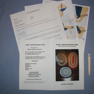 May include: Instructions and supplies for making an oval toothbrush rug. The instructions include a diagram of the rug and steps for making it. The supplies include a toothbrush needle, scissors, a clipboard, safety pins, and fabric. The text on the instructions reads "Oval Toothbrush Rug with Illustrated Instructions" and "Les-Sal Designs".