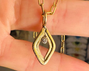 May include: A gold chain necklace with a diamond-shaped pendant featuring a small diamond in the center.