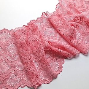 Może przedstawiać: Zbliżenie na różową koronkę z delikatnym falbaniastym brzegiem. Koronka ma kwiatowy wzór i idealnie nadaje się do dodania odrobiny elegancji do każdego projektu.