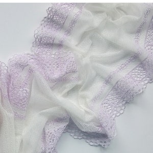 May include: White and lavender lace fabric with a delicate pattern. The fabric is soft and sheer, and it has a scalloped edge.