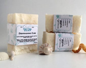May include: Three white bars of dishwashing soap with a label that reads "Sea Clean Soap Dishwashing Cube 4.5 oz". The label also includes the text "Let's remove another plastic bottle from our lives. Rub a wet sponge on the top of the block to gather some soap. Wash dishes as normal and rinse."