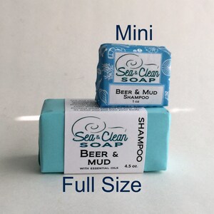 May include: Two bars of soap, one full size and one mini, both labeled "Sea & Clean Soap" and "Beer & Mud Shampoo". The full size bar is light blue and has a label with the text "With Essential Oils" and "4.5 oz". The mini bar is blue and white with a label that says "1 oz".