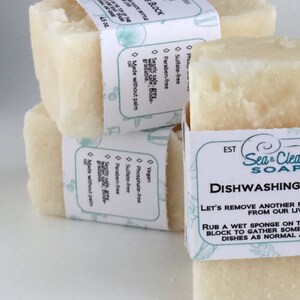 May include: Three bars of white dish soap with labels that say "Sea & Clean Soap" and "Dishwashing". The label also says "Let's remove another film from our lives" and "Rub a wet sponge on the block to gather some suds and wash dishes as normal."
