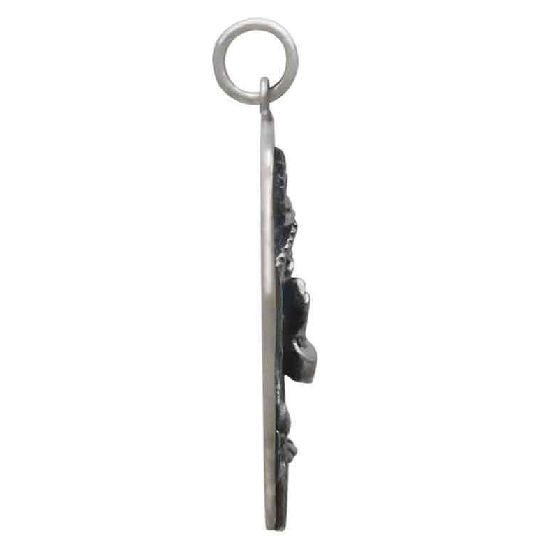 Op de afbeelding: Een zilverkleurige hanger met een gedetailleerd ontwerp van een figuur, mogelijk een religieus icoon. De hanger heeft een lus voor een ketting en wordt gepresenteerd tegen een witte achtergrond. Het ontwerp is ingewikkeld en lijkt van metaal te zijn.