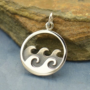 May include: A silver charm pendant in the shape of a circle with three waves cut out of the center. The waves are stylized and have a textured surface.