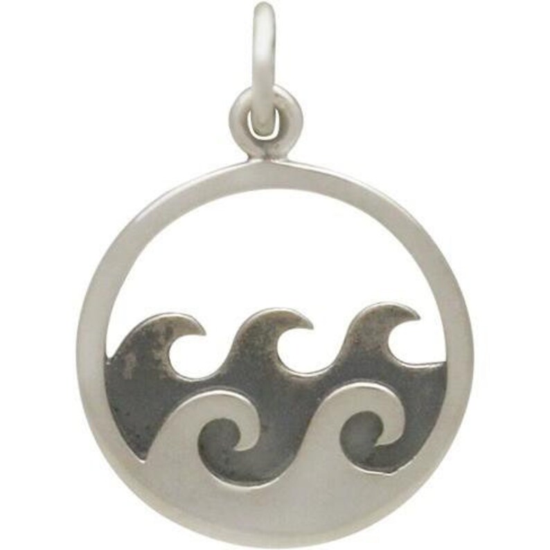 May include: Silver charm with a circle design featuring three waves cut out of the metal. The waves are silhouetted against a black background.