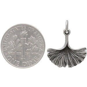 May include: A silver charm in the shape of a ginkgo leaf. The charm is about the size of a dime.