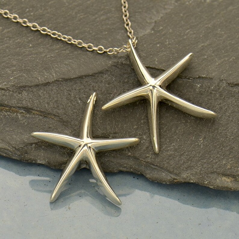 May include: A silver necklace with two silver starfish pendants. The starfish are three-dimensional and have a smooth, polished finish.