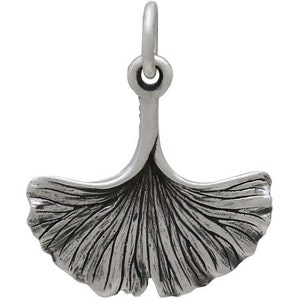 May include: A silver charm in the shape of a ginkgo leaf. The leaf is detailed with veins and has a loop at the top for attaching to a bracelet or necklace.