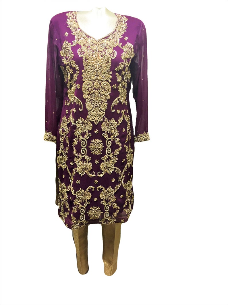 Puede incluir: Un vestido largo de manga larga morado con bordados dorados y pantalones dorados a juego.