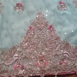 May include: A light blue fabric with silver and pink embellishments. The fabric has a delicate, lacy design with small beads and sequins.