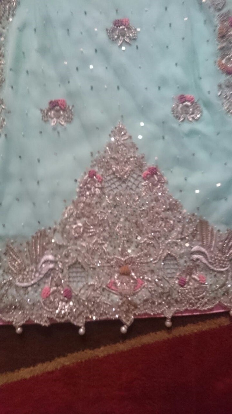 May include: A light blue fabric with silver and pink embellishments. The fabric has a delicate, lacy design with small beads and sequins.