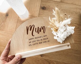 May include: Wooden sign with a half-circle shape, decorated with dried flowers. The sign says "Mum" and "Happy Mother's Day! We love you so much Leo, Lilette and Loni XO".