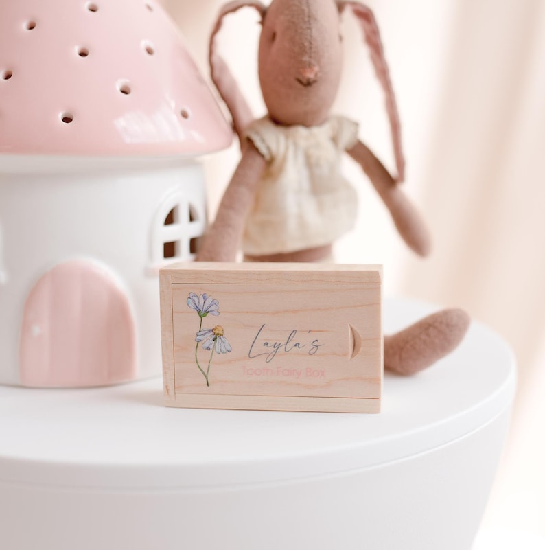 May include: A wooden tooth fairy box with a floral design and the text "Layla's Tooth Fairy Box".