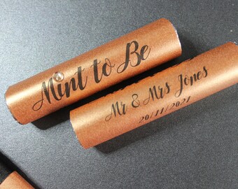 May include: Two copper-colored tubes with a decorative design. The top tube has a small rhinestone and says "Mint to Be". The bottom tube says "Mr & Mrs Jones 20/11/2021".