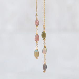 May include: A pair of long, gold chain earrings with oval-shaped gemstones. The gemstones are a mix of pink, green, and iridescent colours.